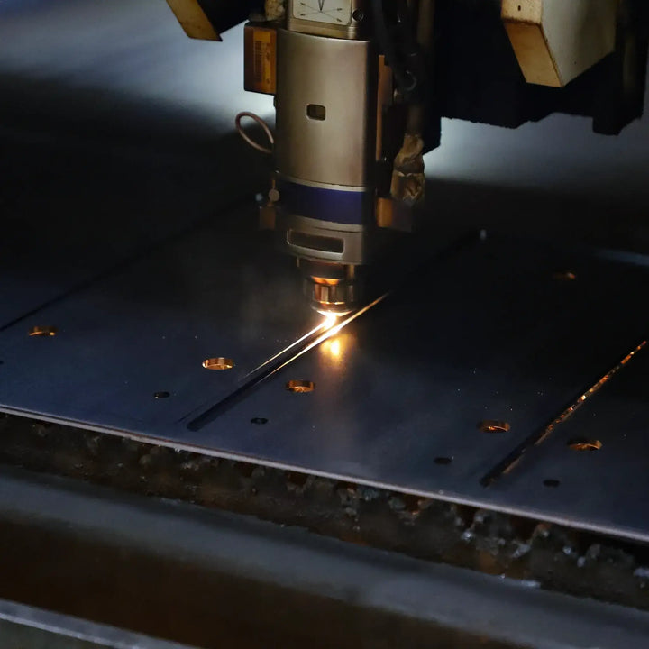 Close-up of a CNC laser cutting machine in action, cutting steel with precision and efficiency in an industrial setting.