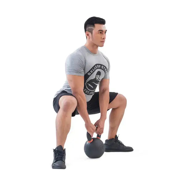 Man performing squat with powder-coated kettlebell, gym equipment Vancouver, fitness training, home gym solutions, exercise equipment